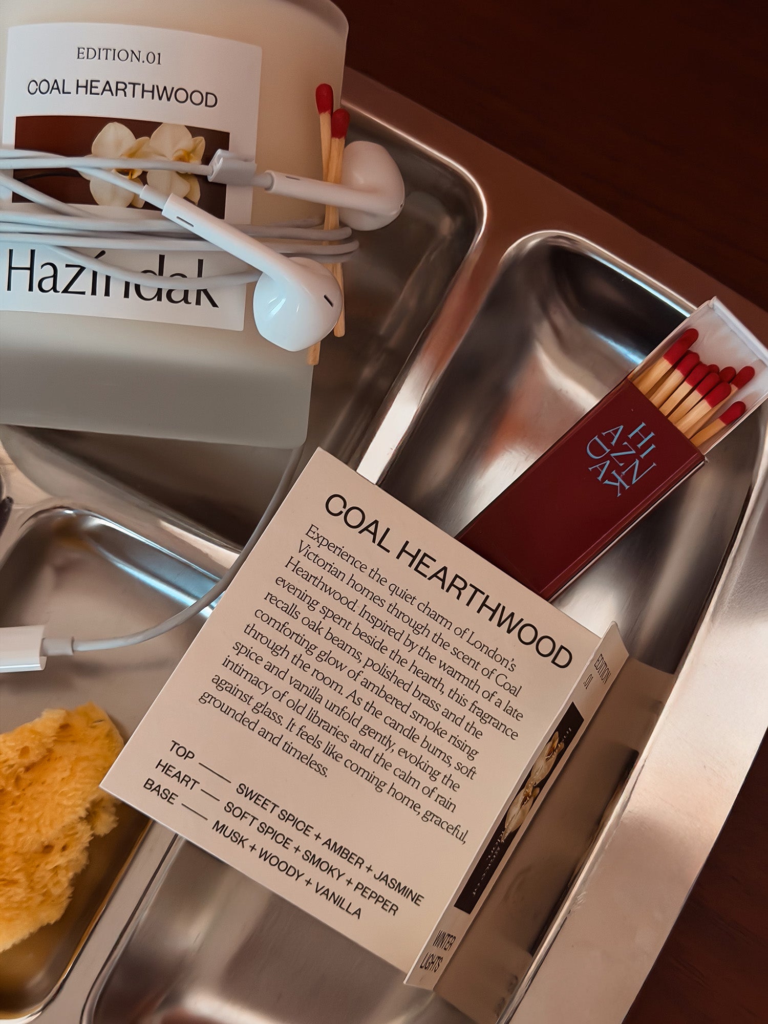 A lit Hazindak Coal Hearthwood candle placed on a tray, creating a cozy and warm home atmosphere.