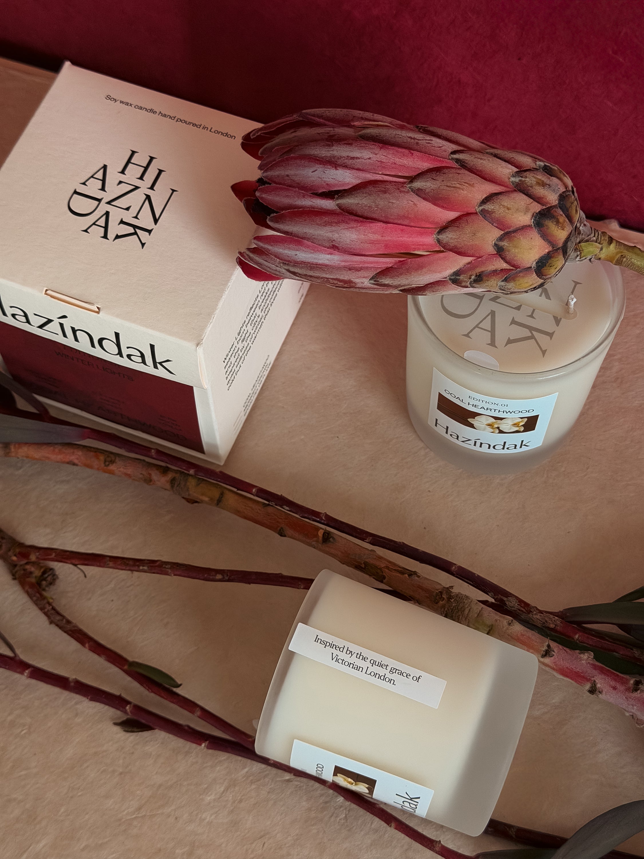A lit Hazindak Coal Hearthwood candle placed with flower creating a cozy and warm home atmosphere.